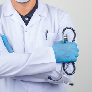 Doctor crossing arms while holding stethoscope in white coat fro